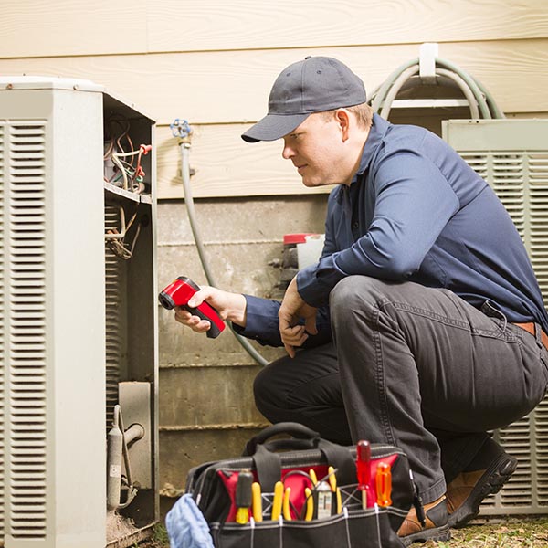 Air conditioner repairmen work on a home's air conditioner unit outdoors.