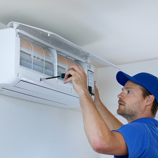 hvac services - technician installing air conditioner on the wall at home